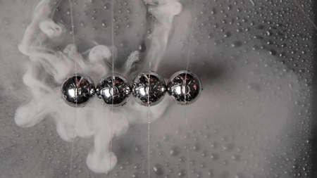Image of wet steel newton balls with smoke, top view