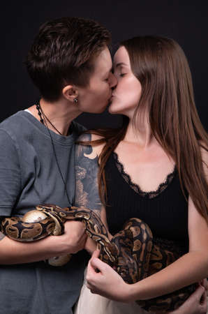 Photo of two kissing women with pythonsの写真素材