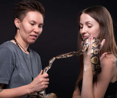 Photo of women with two kissing pythons