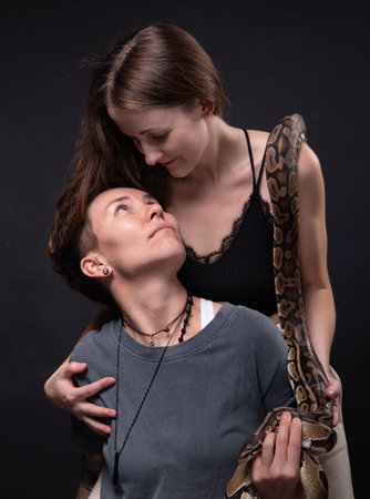 Photo of two hugging women with snake on shouldersの写真素材