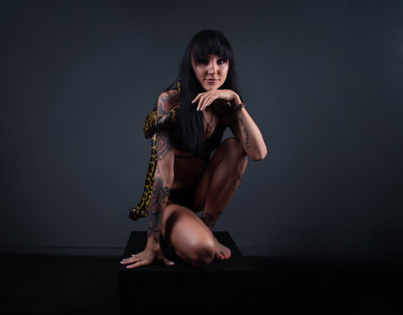 Photo of the brunette woman squatting with pythonの写真素材