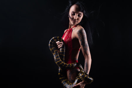 Image of brunette woman with blowing hair holding snakeの写真素材
