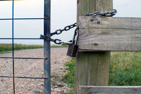 chain and lock on a gate leading to a pathの写真素材