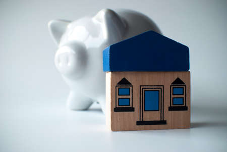 wooden toy house and piggy bank on white backgroundの写真素材