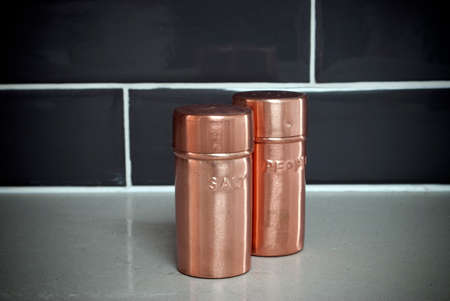 Copper salt and pepper shakers on kitchen benchtop