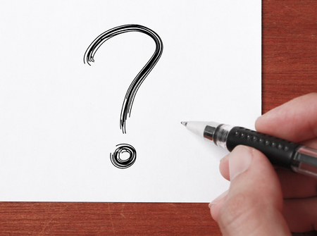 Hand with black pen is writing   Big Question Mark on white paper.の写真素材