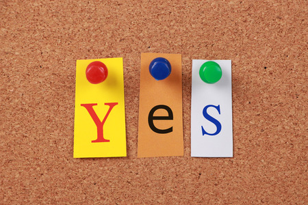 The word Yes in cut out magazine letters pinned to a corkboard.の写真素材