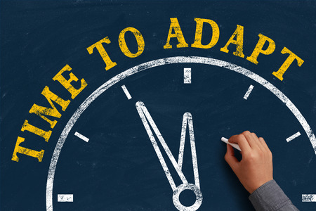 Businessman is drawing the concept of time to adapt on chalkboard.の写真素材