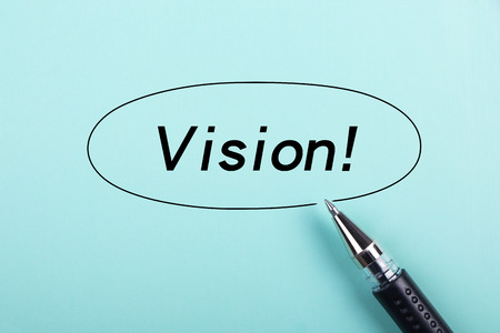 Vision text is on blue paper with black ball-point pen aside.の写真素材