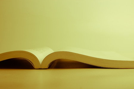 An opened book laying on the blank surface. Yellow light.の写真素材
