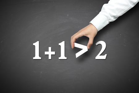 Business Synergy concept with businessman hand holding against blackboard background.