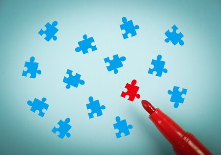 Puzzle concept is on blue paper with a red marker aside.の写真素材