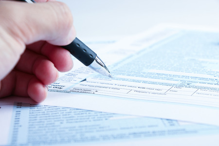 A person is completing the tax form with a pen.