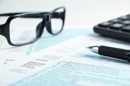 Tax form business financial concept with a pen, a pair of glasses and a calculator aside.の写真素材