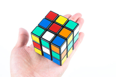 Rubik's cube is holden by hand isolated on white background.のeditorial素材