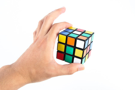 Rubik's cube is holden by hand isolated on white background.のeditorial素材