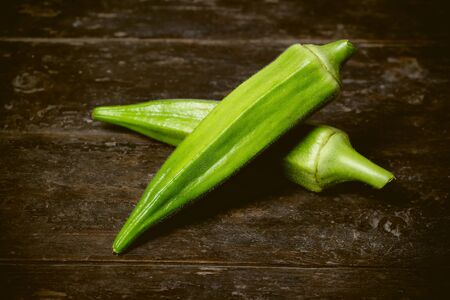 Farm fresh raw okra on wooden rustic table.