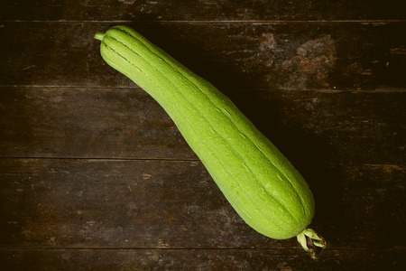 Green Sponge Gourd is on the wooden floor background.