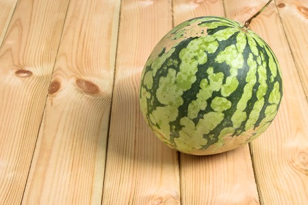 A watermelon is on the wooden background.の写真素材