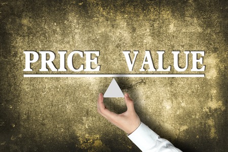 Price Value Balance concept with scale holden by businessman hand against the old background.