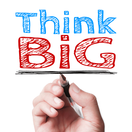 Hand with pen is writing the text Think big on the transparent whiteboard.の写真素材