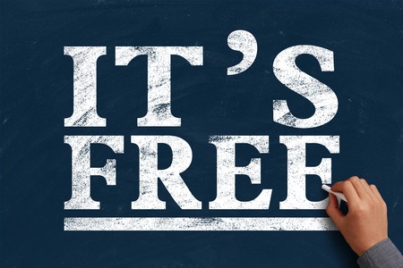 Hand with chalk is writing the text It is Free on the blue chalkboard.の写真素材