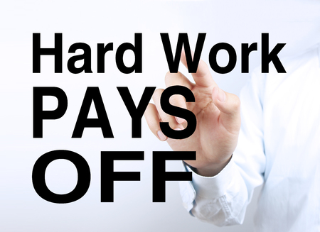 Businessman is pointing the text Hard Work Pays Off on the virtual transparent screen.の写真素材