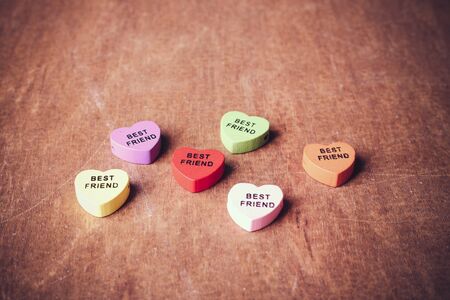 Some colorful hearts with text Best Friend on the wooden table.