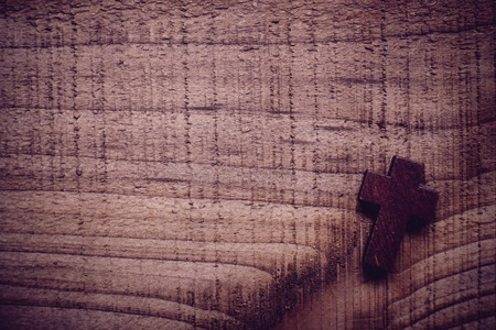 Wooden cross lying on the rustic wooden background.の写真素材