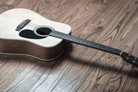 Closeup shot of acoustic guitar on wood background.