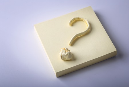 Question mark made of yellow sticky note is on white background.の写真素材