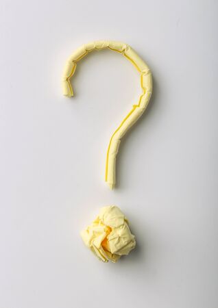 Question mark made of yellow sticky note is on white background.の写真素材