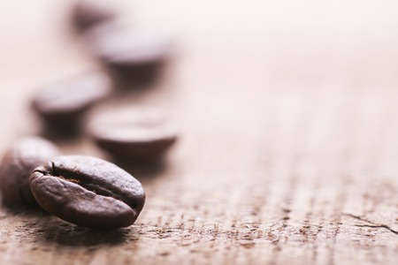 Some coffee beans are on the wooden background.