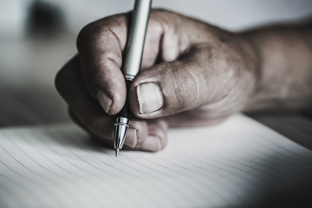 Close shot of a human hand writing something on the paper.の写真素材