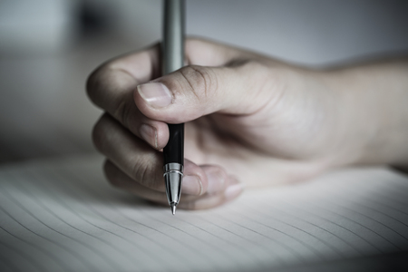 Close shot of a human hand writing something on the paper.の写真素材