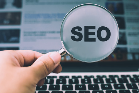 SEO concept on magnifying glass with the background of computer.