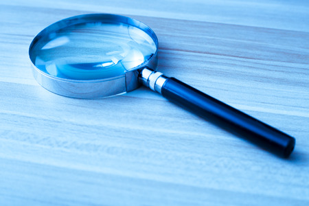 Magnifying glass with the wooden table bakcground.