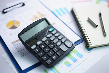 Office workplace with finance charts and calculator on table of office.