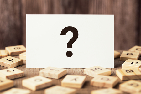 Question Mark sign on the wooden table with wooden background.