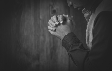 Praying hands against dark background.の写真素材