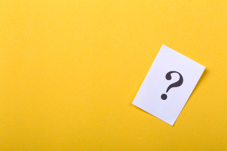 White paper with question mark against yellow background.の写真素材