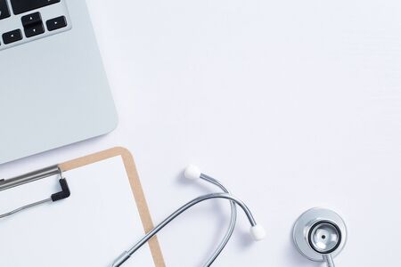 Workplace of doctor with laptop and stethoscope and notebook on white table top view shot.の写真素材