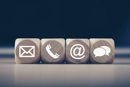 Contact Methods. Close-up of a phone, email, chat and post icons wooden block.の写真素材