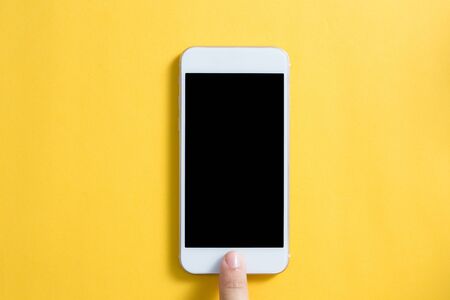 Blank smartphone with hand isolated on yellow background.の写真素材