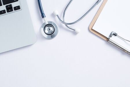 Workplace of doctor with laptop and stethoscope and notebook on white table top view shot.の写真素材