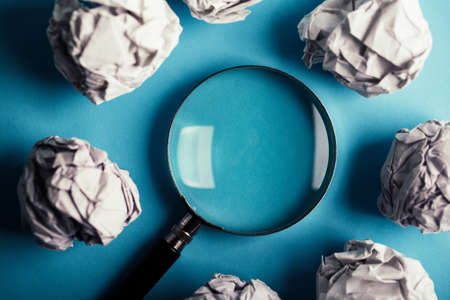 Magnifying with crumpled paper ball on the blue background.の写真素材