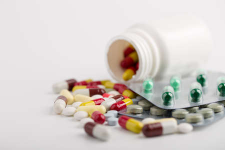 Assorted pharmaceutical medicine pills, tablets and capsules over white background.の写真素材