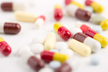 Assorted pharmaceutical medicine pills, tablets and capsules over white background.の写真素材
