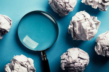 Magnifying with crumpled paper ball on the blue background.の写真素材