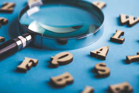Magnifying with wooden alphabets around on the blue background.の写真素材